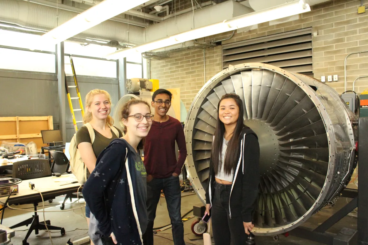 Students pose with a wind turbine.