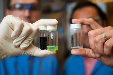 Two researchers holding up three vials of sustainable fuels.