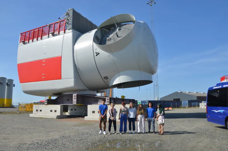 Students pose in front of a wind turbine in Denmark.