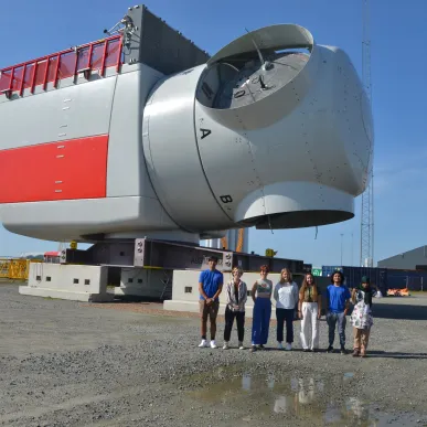 Six MIT students stand in front of a large piece of machinery in Denmark.