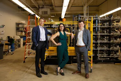 The co-founders of Via Separations (Shreya Dave PhD ’16, flanked by professors Jeffrey Grossman and Brent Keller)  stand in front of industrial equipment